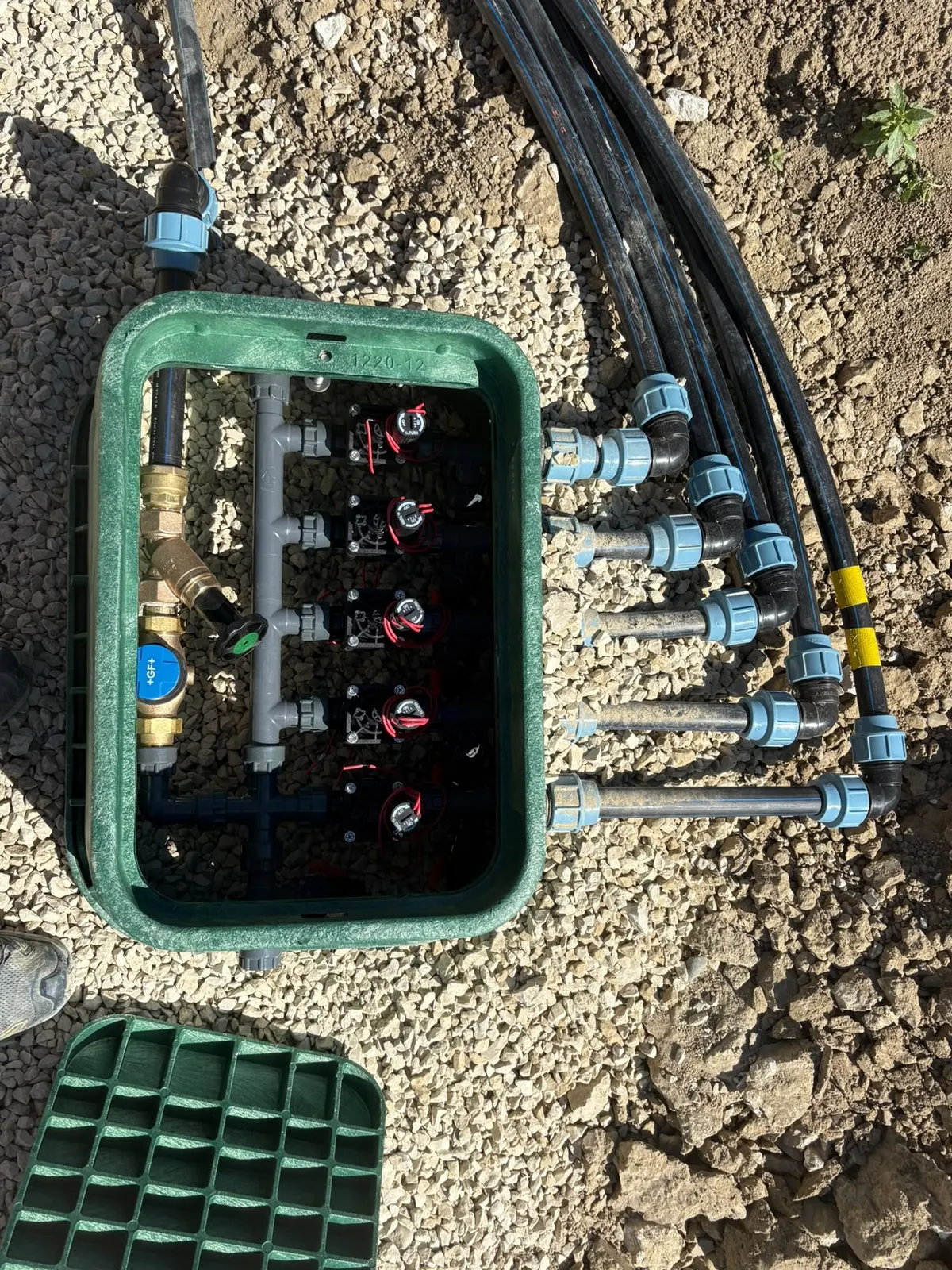 Regard vert avec électrovannes et raccordements, posé dans le gravier
